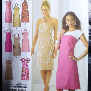 May include: Simplicity sewing pattern featuring various dress designs. The pattern includes images of dresses with different necklines, straps, and pocket styles. The models are wearing dresses. The text "design your own" is visible.