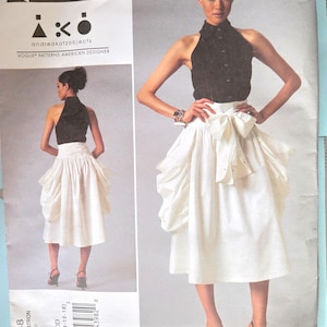 May include: A sewing pattern featuring a woman wearing a black halter top and a white skirt with a large bow. The pattern is labeled "CUTTING EDGE" and "VOGUE PATTERNS AMERICAN DESIGNER". The pattern number is V1248, with sizes DD (12-14-16-18).