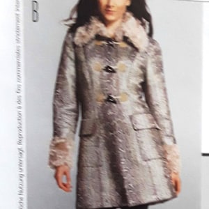 May include: A long-sleeved, gray and white patterned coat with a faux fur collar. The coat has a double breasted closure with large buttons and a belt.