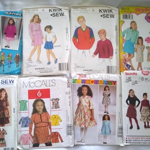 May include: A collection of vintage sewing patterns for children's clothing. The patterns feature illustrations of dresses, skirts, and tops. Brands include Kwik Sew, McCall's, Simplicity, and Burda. The patterns are in various sizes and styles.