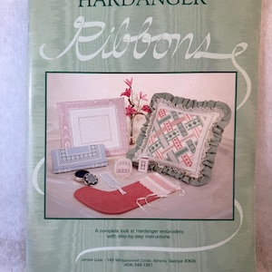 May include: A softcover instructional book titled Hardanger Ribbons with a light green cover. The cover features a photograph of various Hardanger embroidery projects, including a ruffled pillow, a stocking, and small decorative items.