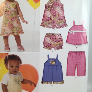 May include: A sewing pattern for baby clothes. The pattern includes four different designs: a floral print dress, a floral print bloomers, a pink gingham top with a white lace trim, and a blue denim overall. The pattern is from New Look Patterns.