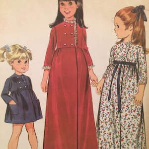 May include: Three girls wearing different styles of dresses. The girl on the left is wearing a blue dress with a white collar and buttons. The girl in the middle is wearing a red dress with a white collar and buttons. The girl on the right is wearing a white dress with a floral pattern and a blue sash.