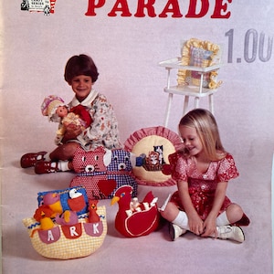 May include: A craft pattern booklet with the title "PILLOW PARADE" and the subtitle "PILLOWS FOR YOUNG AND OLD ALIKE". The cover features a colorful illustration of children playing with various animal-shaped pillows, including a red and blue bear, a yellow and white ark, and a red hen.