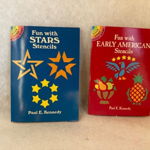 May include: Two Dover Little Activity Books by Paul E. Kennedy. The blue book is titled Fun with STARS Stencils and features yellow star designs. The red book is titled Fun with EARLY AMERICAN Stencils and features a blue eagle and fruit.