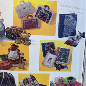 May include: A collection of craft projects featuring various fabric designs. The projects include a small quilted purse, a fabric-covered photo album, a fabric-covered box, and a fabric-covered tea cozy. The image also includes a small fabric-covered mouse and a fabric-covered keyboard.
