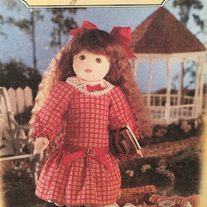 May include: A Betsy McCall doll wearing a red plaid dress with a matching bow and belt. The doll has long brown hair and is holding a small book. The background includes a gazebo and picnic basket.