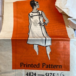 May include: Vintage sewing pattern for a sleeveless dress with a geometric design. The pattern is printed on orange paper and includes the number 4824 and the size 16.