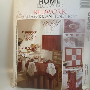May include: McCall's Home Decorating Redwork: An American Tradition sewing pattern featuring a red and white kitchen with a table, chairs, and various redwork embroidery designs. The pattern includes instructions for making a tablecloth, placemats, a valance, and an apron.