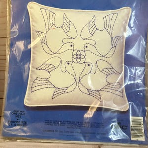May include: A white pillow with a line stitching pattern of four doves. The pillow is packaged in a clear plastic bag with a blue background. The packaging includes the brand name "Colortex" and the text "Line Stitching". The finished size of the pillow is 12 x 12 inches.