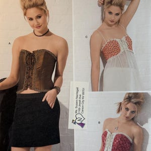 May include: A fashion image featuring three different corset designs. One is a brown corset with lace-up detailing, paired with a black skirt. Another is a red and white corset top. The third is a peach and white corset top. The image is from a Simplicity pattern.