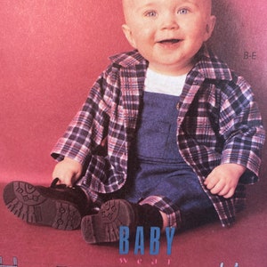 May include: A baby wearing a blue denim overall with a plaid shirt over it. The baby is sitting on a pink background. The image also shows several other clothing items for babies, including a blue plaid shirt, a blue denim overall, a blue denim dress, a blue denim shirt, and a floral print overall.