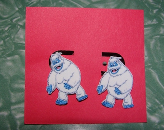 May include: Two cartoon yeti stickers on a red background. The yeti is white with blue accents on its feet and hands, and a blue mouth. The background is a solid red color with the letter "E" cut out.