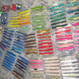 May include: A large collection of embroidery floss skeins organized on plastic bobbins and packaged in individual clear plastic sleeves. The assortment features a wide spectrum of colors including shades of blue, green, yellow, red, pink, brown, and white.