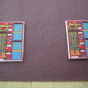 May include: Two red and white Bingo scratch-off tickets with the text "Bingo $10,000" on each ticket.