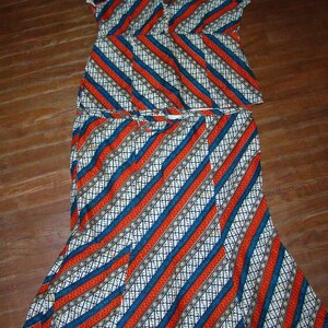 May include: A two-piece outfit with a white, blue, and orange diagonal striped pattern. The top has short sleeves and a V-neck. The skirt is a full skirt with a fitted waist.