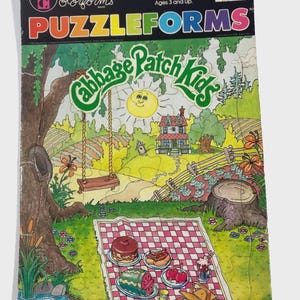 May include: A vintage 30-piece "Cabbage Patch Kids" puzzle by Colorforms. The colorful puzzle features a picnic scene with a red and white checkered blanket, food, and a smiling sun. The puzzle is designed for ages 3 and up.