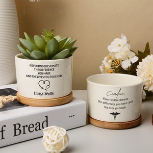 May include: Two cream ceramic plant pots with bamboo saucers. One holds a succulent and the text: "Never underestimate the difference you made and the lives you touched." The other pot has the text: "Candice, Never underestimate the difference you make and the lives you touch."