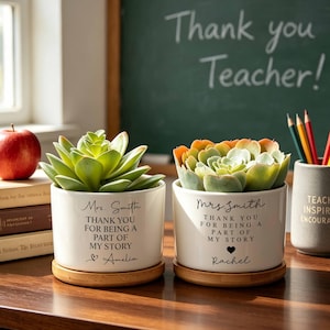 May include: Two white ceramic cylindrical planters with bamboo saucers, each containing a green succulent. The planters feature black printed text reading "Mrs. Smith THANK YOU FOR BEING A PART OF MY STORY" followed by a name and a small heart icon.