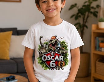 May include: A white short-sleeved t-shirt featuring a colorful graphic of various dinosaurs, lush green foliage, a volcano, and a red shield emblem with the text OSCAR 6 printed in bold white letters across the center of the chest area.