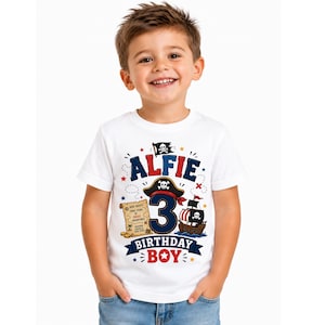 May include: A white short-sleeved t-shirt featuring a pirate-themed graphic with the name Alfie, the number 3, a pirate hat, a treasure map, and a ship. The text reads Alfie, 3, Birthday Boy, and Ahoy Matey! Three Years of Pirate Adventures.