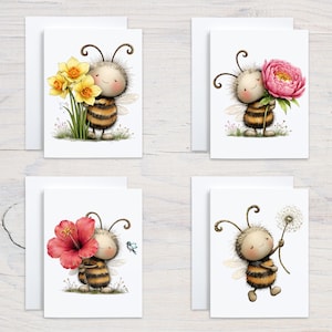 May include: Set of four greeting cards featuring a cartoon bee character holding different flowers: daffodils, a pink peony, a red hibiscus, and a dandelion. Each card has a white envelope.