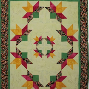 May include: A quilt with a green, yellow, and pink star pattern. The quilt is quilted with a design of frogs and leaves.