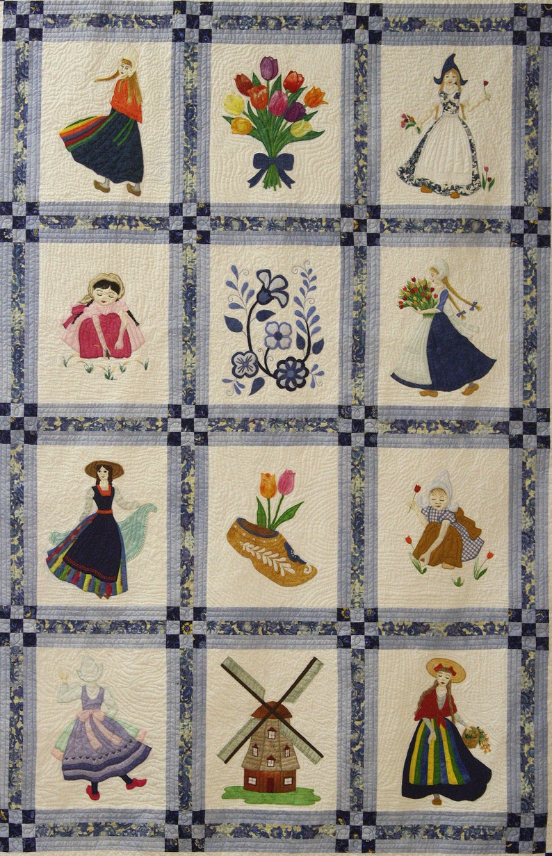 K&ouml;nnte beinhalten: Eine wei&szlig;e Steppdecke mit einem blauen und wei&szlig;en Rand. Die Steppdecke ist in neun Quadrate unterteilt, jedes mit einem anderen gestickten Design. Die Designs beinhalten ein M&auml;dchen in einem blauen Kleid, ein M&auml;dchen in einem roten Kleid, ein M&auml;dchen in einem gelben Kleid, ein M&auml;dchen in einem gr&uuml;nen Kleid, ein M&auml;dchen in einem lila Kleid, ein M&auml;dchen in einem rosa Kleid, ein M&auml;dchen in einem braunen Kleid, ein M&auml;dchen in einem wei&szlig;en Kleid und ein M&auml;dchen in einem blauen Kleid. Die Designs beinhalten auch eine Windm&uuml;hle, ein Paar Holzschuhe, einen Tulpenstrau&szlig; und ein Blumenmuster.
