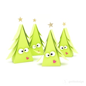 May include: Four green paper Christmas tree boxes with googly eyes and pink hearts. The boxes are decorated with gold glitter stars.