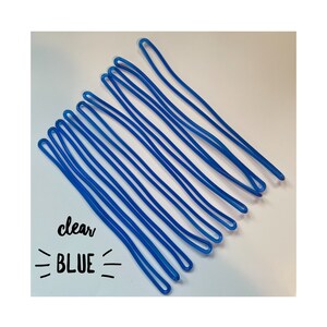 May include: A group of ten clear blue rubber bands, arranged in a fan shape on a white surface. The text "clear BLUE" is written below the rubber bands.