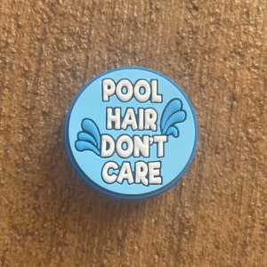 May include: Blue and white charm with the text "Pool Hair Don't Care" and a water splash design.