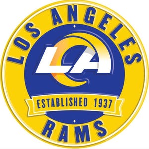 May include: A circular Los Angeles Rams logo in yellow, blue, and white. The words "LOS ANGELES" and "RAMS" are in blue around the yellow border. The center features a white "LA" logo over a blue background, with "ESTABLISHED 1937" in a banner.