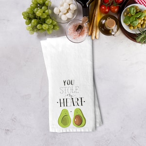 May include: White kitchen towel with the text "You stole my heart" and two avocado illustrations with smiling faces.