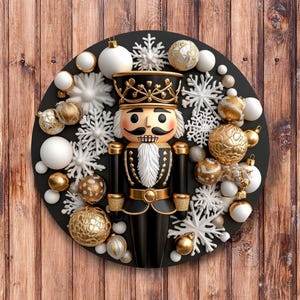May include: A Christmas decoration featuring a black and gold nutcracker surrounded by white snowflakes and gold and white baubles. The nutcracker wears a black uniform with gold details. Set against a wooden background.