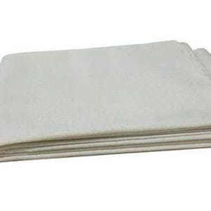 Puede incluir: Tela plegada de color blanquecino, probablemente lino o algodón, con textura visible. La tela está cuidadosamente apilada, mostrando múltiples capas. Los bordes son limpios y rectos, lo que sugiere un producto terminado. La apariencia general es simple y neutra.