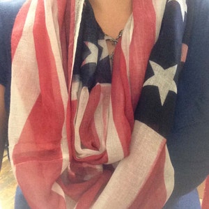 Puede incluir: Una bufanda infinita roja, blanca y azul con un patrón de estrellas y rayas. La bufanda está hecha de una tela suave y ligera, perfecta para agregar un toque de patriotismo a cualquier atuendo.