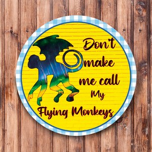 May include: A yellow circle with a blue and white checkered border. The circle has a silhouette of a flying monkey with the text "Don't make me call my Flying Monkeys".