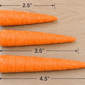 May include: Three orange carrot-shaped objects with textured surfaces. The top carrot measures 2.5 inches in length, the middle carrot measures 3.5 inches in length, and the bottom carrot measures 4.5 inches in length as indicated by markers.