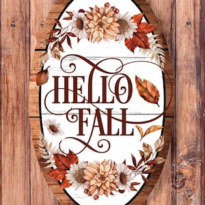 May include: Oval wooden sign with a white background and a brown wooden frame. The sign features a wreath of fall leaves and flowers with the text "HELLO FALL" in brown script.