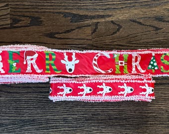 May include: Red Christmas ribbon with white text that reads "MERRY CHRISTMAS". The ribbon features festive images of a reindeer, candy cane, and Christmas tree. A smaller matching ribbon piece is also present.