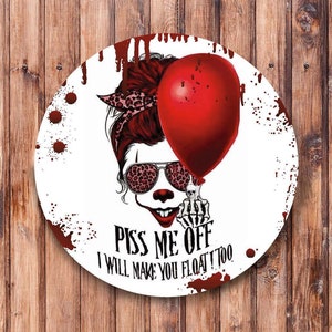 Könnte beinhalten: Ein runder weißer Aufkleber mit einer roten und schwarzen Illustration eines Schädels, der eine Sonnenbrille und eine rote Schleife trägt. Der Schädel hält einen roten Ballon. Der Text "Piss Me Off I Will Make You Float Too" ist in rot unter dem Schädel geschrieben.