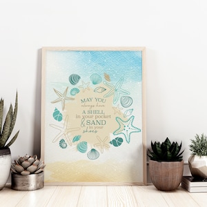 May include: A framed print with a beach theme. The artwork features a watercolor background with blue and tan hues. The text reads "May you always have a shell in your pocket & sand in your shoes." Decorative starfish and seashells surround the text.