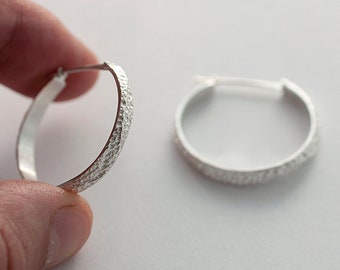 Hoop earrings. Hoop with irregular and organic texture. Inspired by sea waves, in texture and shape. Round shiny silver earrings