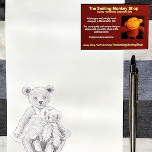 May include: A black and white pen and ink drawing of two teddy bears sitting together. The larger bear is wearing a dress and holding the smaller bear. The drawing is on a white background.