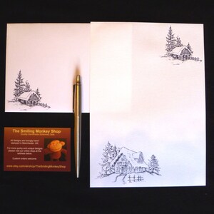 May include: A set of white stationery featuring a black and white illustration of a cabin in the woods. The stationery includes a letterhead, envelope, and business card. The business card has the text "The Smiling Monkey Shop" and a cartoon monkey.