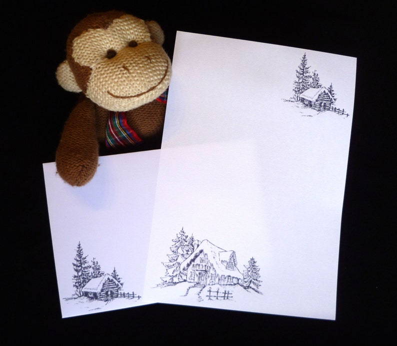 May include: Two white cards with black ink drawings of a cabin in a snowy forest. The cards are blank and ready to be written on.