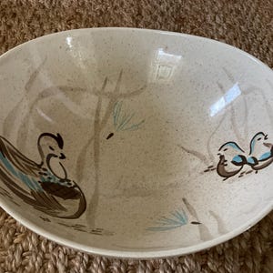 Puede incluir: Bol ovalado de cerámica con fondo beige moteado. El bol presenta ilustraciones pintadas a mano de patos y ramas estilizadas en marrón, verde azulado y azul. Una pieza decorativa para servir alimentos o exhibir.