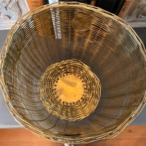 May include: A vintage, open-weave basket with a rounded shape. The basket is made of gold-toned metal wire, with a circular base and a slightly flared top. The interior features a smaller, circular base. The basket is likely used for storage or display.