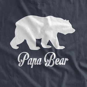 May include: A navy blue t-shirt with a white silhouette of a bear walking and the text "Papa Bear" underneath.