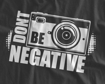 May include: Black t-shirt with a white graphic of a camera and the text "Don't Be Negative".